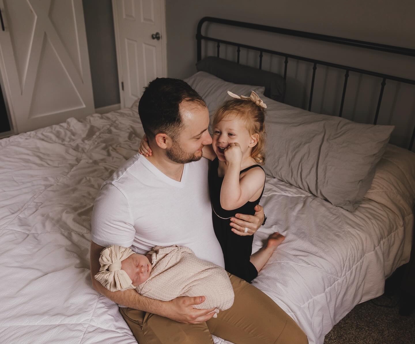 Zac Davis holding his two daughters in his room